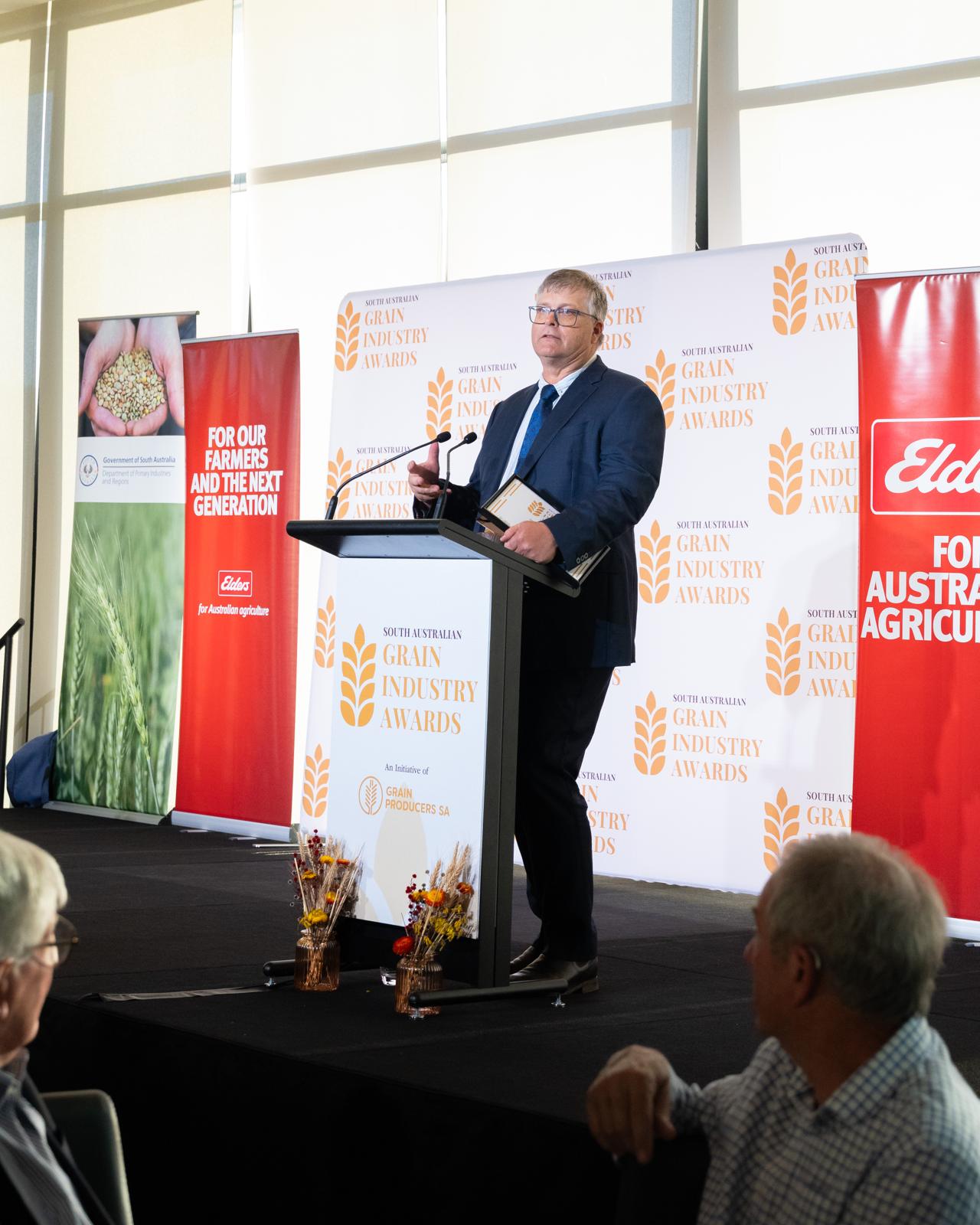 A speaker on stage in front of the Awards backdrop